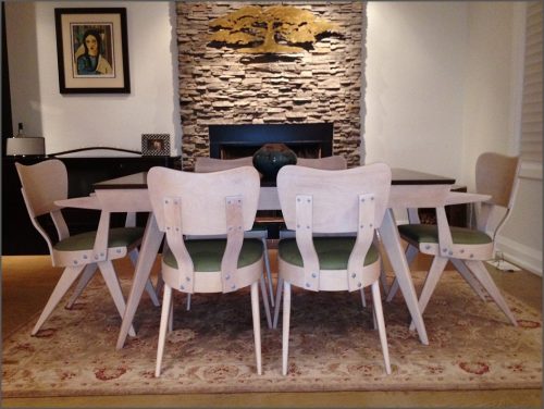 Dining room with table with dark top and white chairs with green seats.