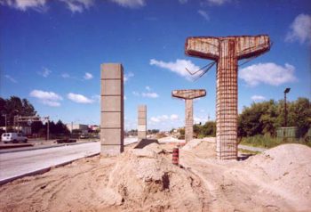 Old and new concrete pillars standing by the side of a new road