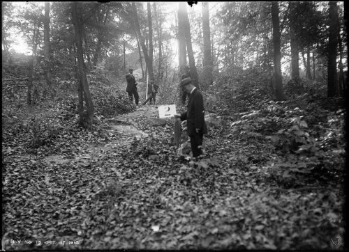 Men in forest, one holding sign.