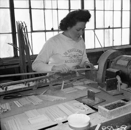 A woman wearing a shirt that says De Havilland Mosquito works at a machine.