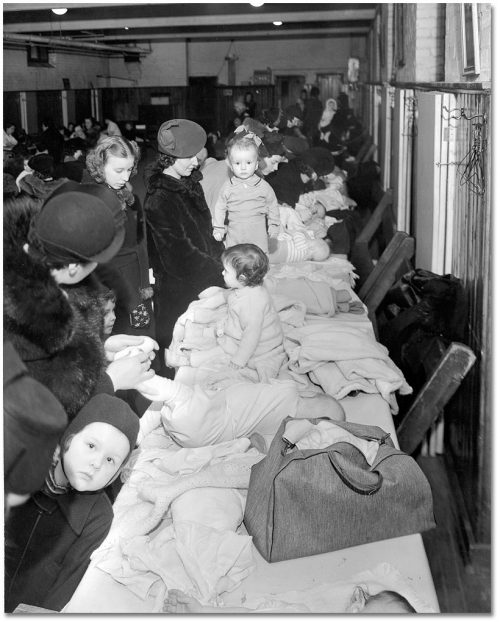 Mothers in winter coats dress babies on a long table covering in clothing.