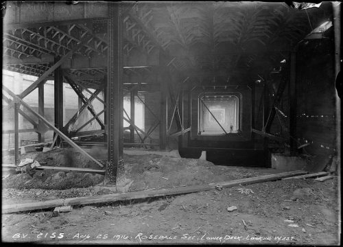 Underneath bridge with riveted metal supports holding it up.