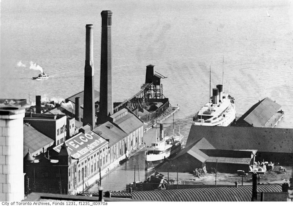 Brick building with two large smokestacks, jutting out into the lake.