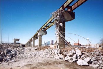 Partial concrete support pillars and a few steel beams, rebar dangling from them, rubble on the ground