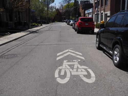 A shared marking on the road consists of a painted bicycle symbol and two arrows, indicating that people cycling must share the road with motorists.