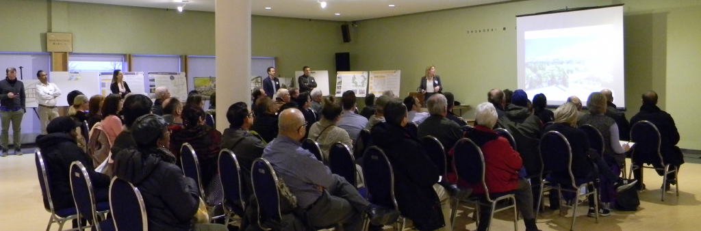 People seated on chairs in rows watching a presentation being given at the front of the room.