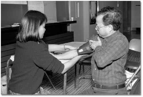 A woman tests a man's blood pressure using a cuff.