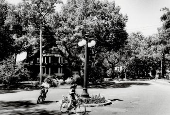 This is an archival photograph of two children on bikes circling a lamppost in Baby Point, taken in 1985