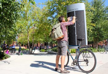 Image of a man putting up his flyer on a postering board