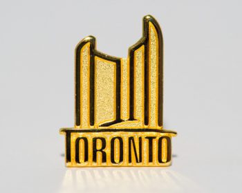 Picture of a City of Toronto Lapel pin featuring two towers and the City Toronto logo