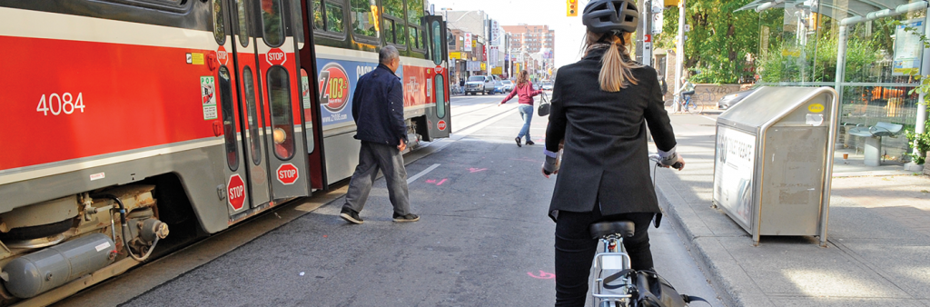 Image of Cyclist waiting for pedestrians to get on and off the TTC streetcar