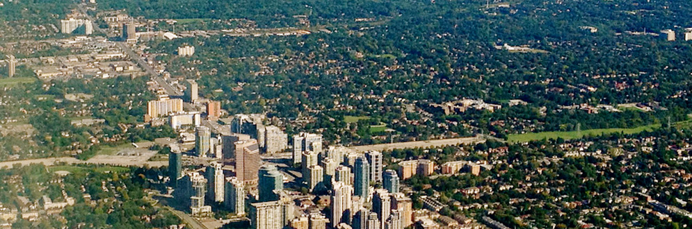 An aerial image of high rise buildings surrounded by low rise neighbourhoods and trees