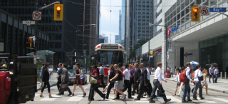 Image of a streetcar and pedestrians crossing through an intersection in the downtown core