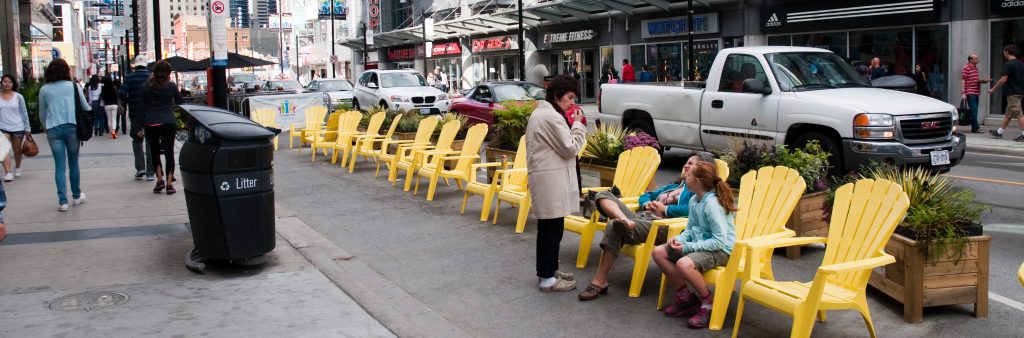 Image of Yonge Street near Dundas square with yellow patio chairs on the curbside lane