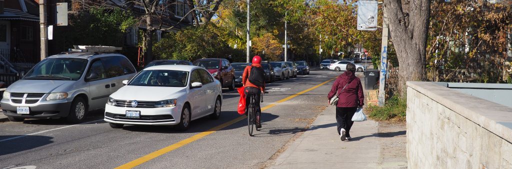 Cyclist heading northbound in the contraflow lane along Bellevue with a car going the opposite direction.