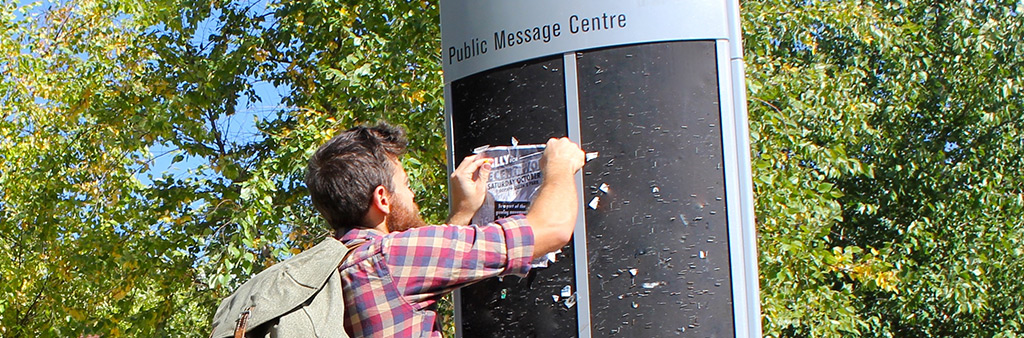 man posting message on Public Message Centre board