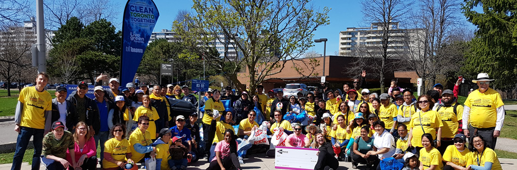 A photograph showing a group of Clean Toronto Together volunteers. Volunteers are posing for a picture, wearing yellow shirts.