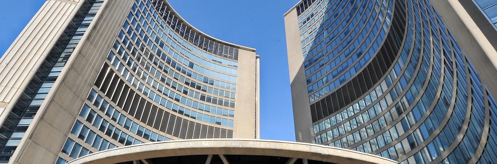 Up close photo of the Toronto City Hall towers and the domed structure the covers the Council Chambers and Members' Lounge.