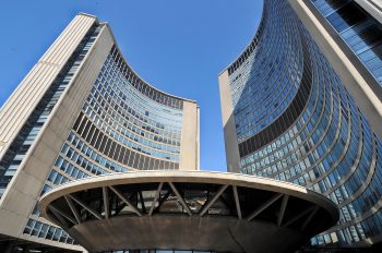 Up close photo of the Toronto City Hall towers and the domed structure the covers the Council Chambers and Members' Lounge.