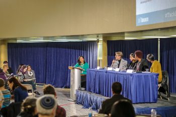 Moderator and panelists speaking to the audience about Livable Incomes and quality jobs on March 12 at City Hall