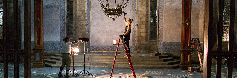 woman standing on step ladder painting a chandelier