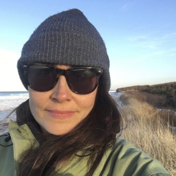 Photograph of Sarah Buell wearing glasses and a toque smiling.