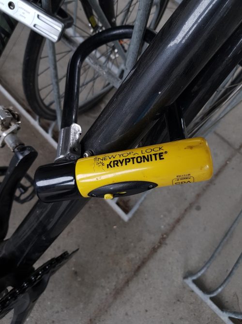 A cyclist uses a U-lock to lock to a bike rack. These locks provide a higher level of security when compared to a cable lock alone.