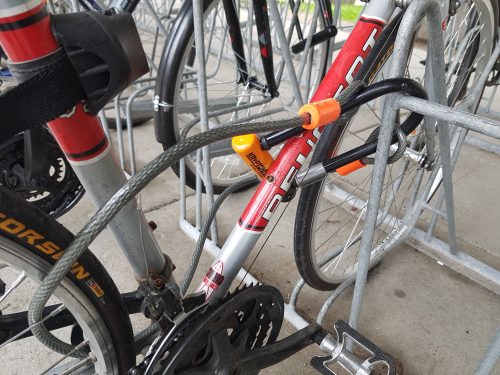 A cyclists uses a U-lock to lock to a rack and a cable to secure both wheels.