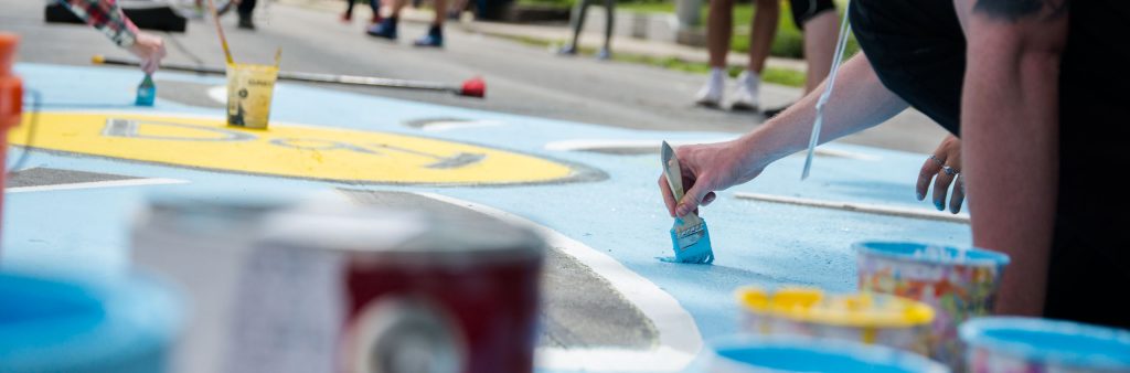 Person painting with blue paint on the road