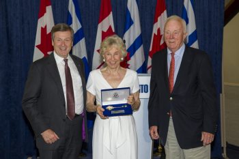 Judy Matthews holds key to the City while smiling for cameras with husband Wilmot and Mayor John Tory at City Hall.