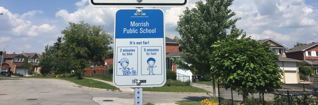 Image of a blue and white street sign reading: Morrish Public School, it's not that far, 2 minutes by bike, 5 minutes by food.