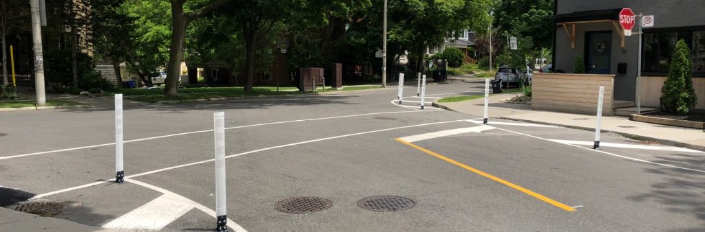 Image of bollards and line paint on the street, which reduces the crossing distance