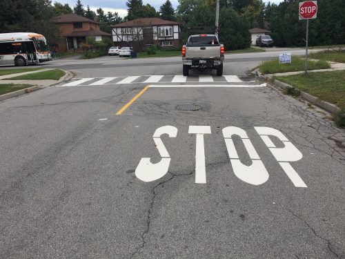 image of a road with pavement markings and a stencil that reads stop