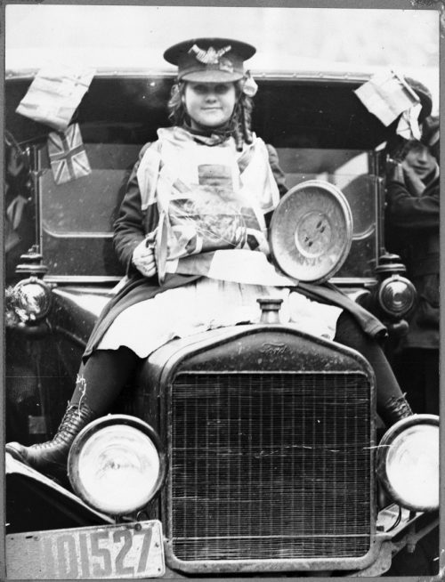 Girl on hood of car during Armistice Day celebrations