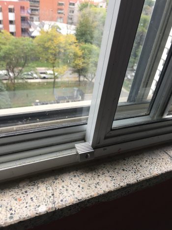 close-up of a window safety device on an apartment window overlooking trees