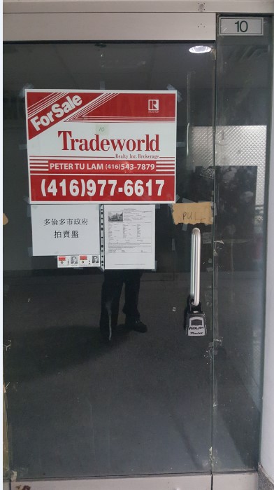 View of entry way to 222 Spadina Avenue with for sale sign. Unit 10 is located one level below street level
