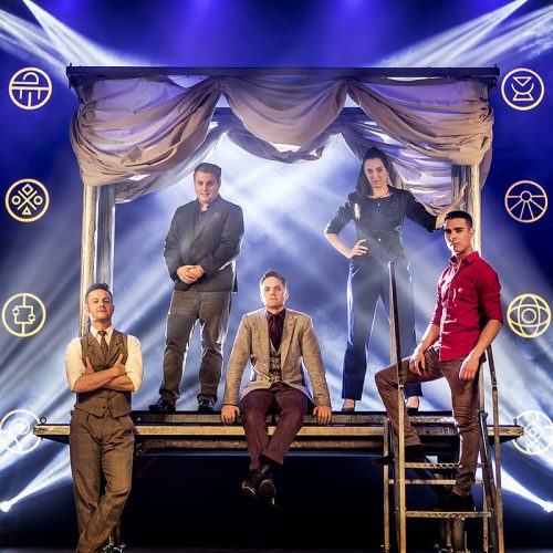 One female and 4 male performers posing on a stage