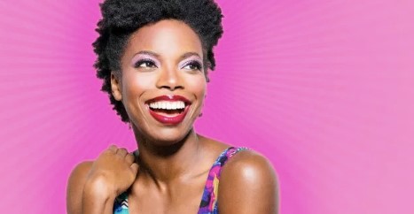 Photo info: Sasheer Zamata. Woman smiling. pink background