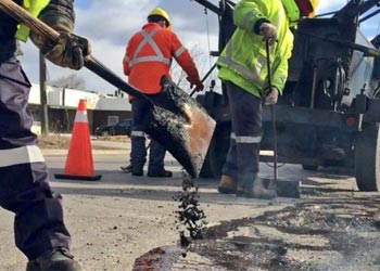 City road maintenance crew filling potholes with asphalt