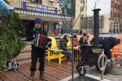 Man playing an instrument on the curbspace of King Street