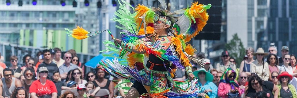 Dancer in bight traditional clothing performs in front of a crowd.