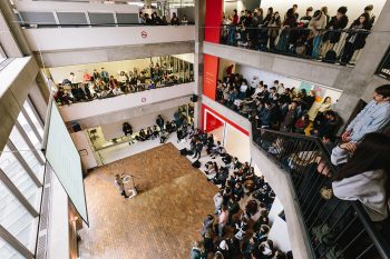 A group of students crowded around a speaker.