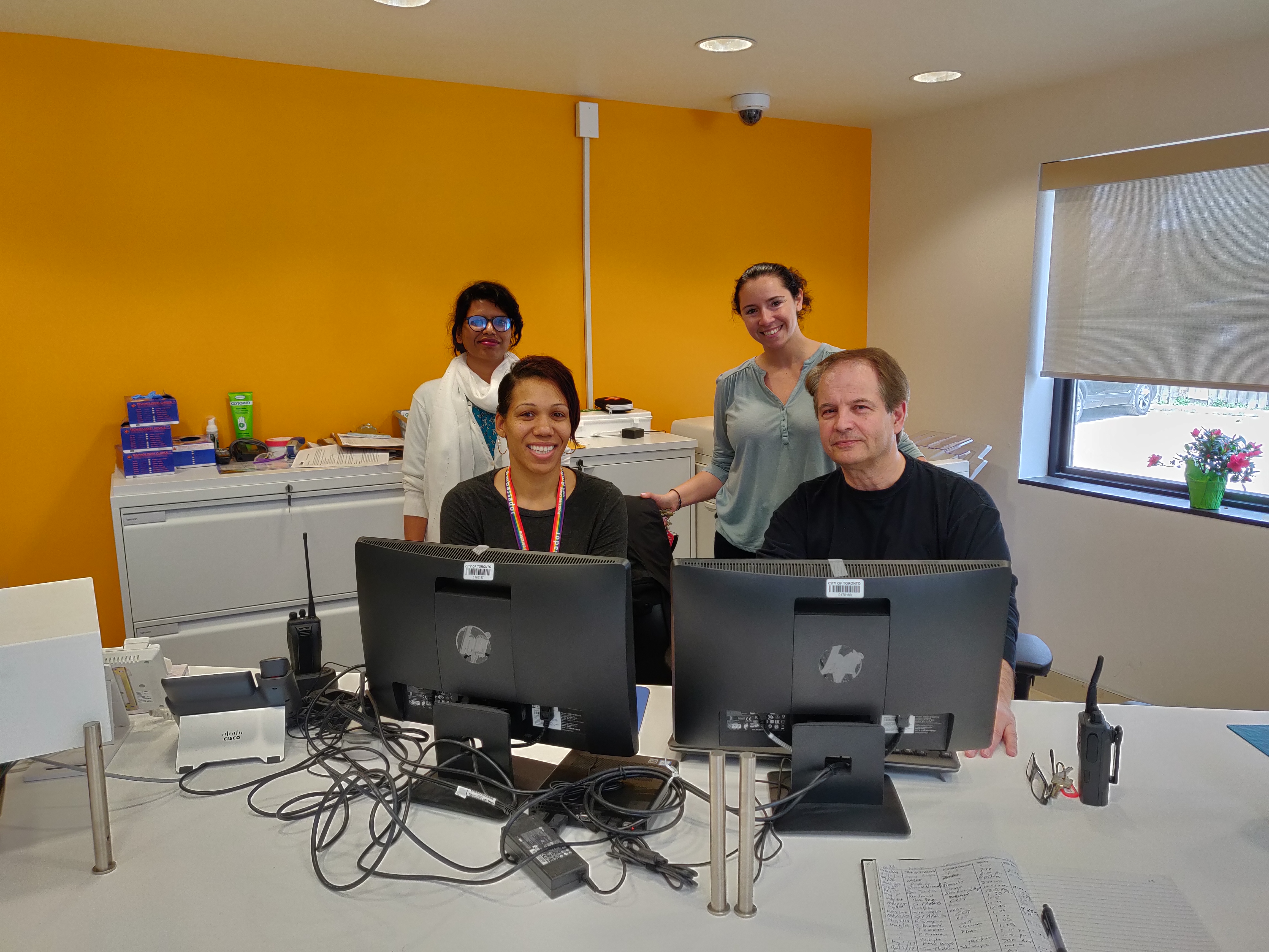 3 women and a man sitting behind a counter at the front desk of a new shelter