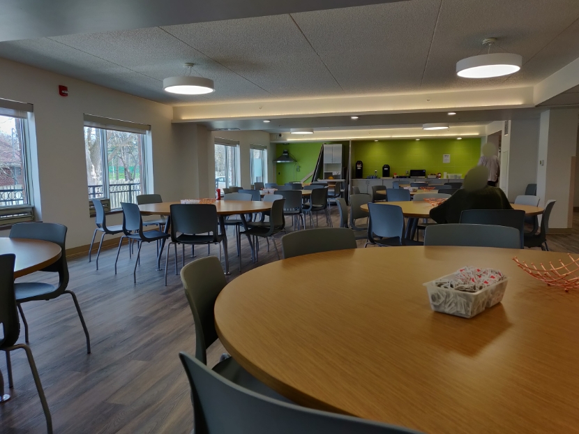 A few rounded tables and chairs in the dining area facing large windows at the Scarborough Village Residence