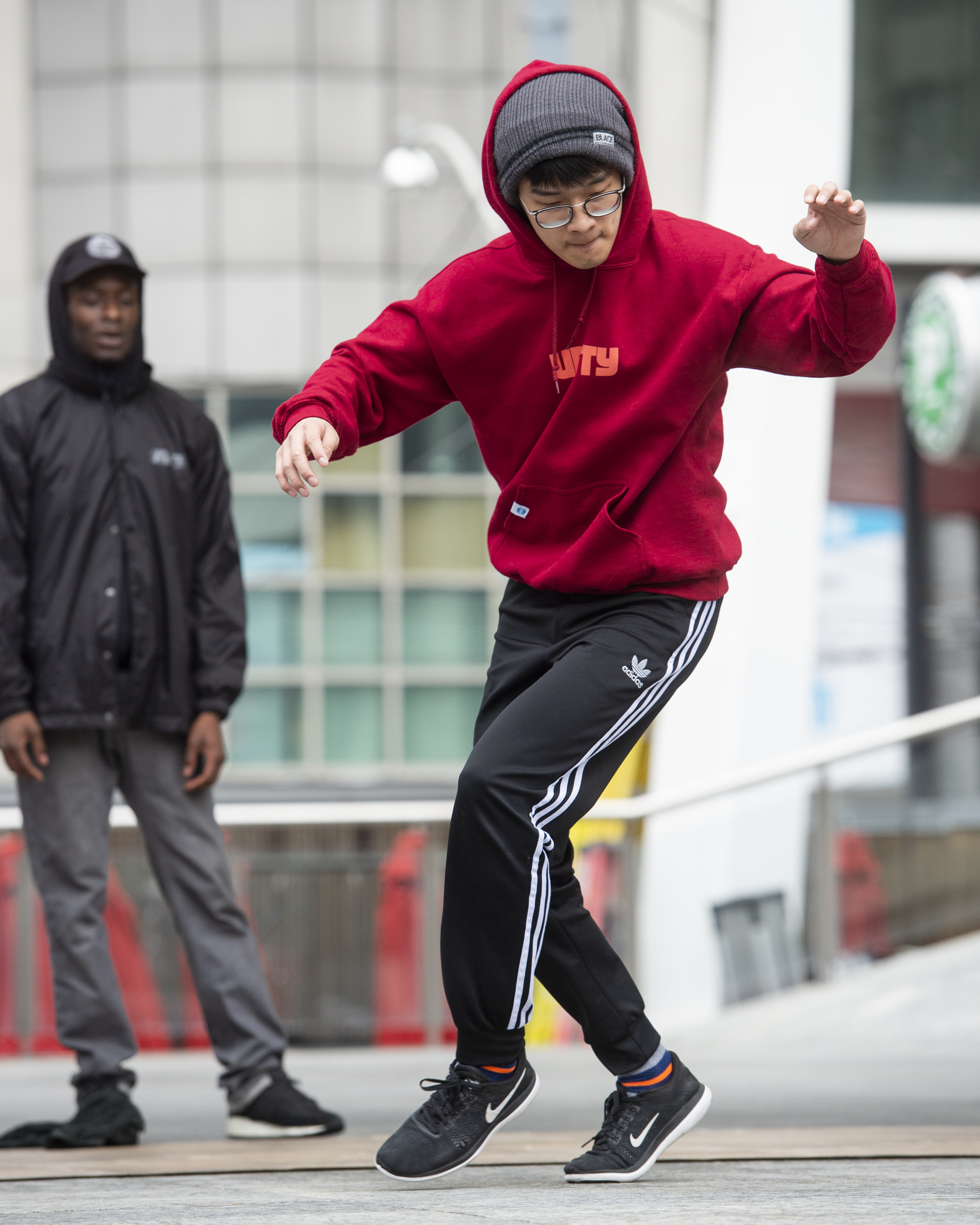 Unity break dancer performing, wearing black track pants and a red hoodie