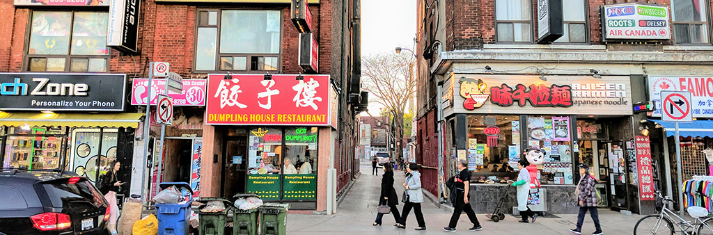 A group of attached historic buildings 3 storeys in height occupied by different retail tenants in Toronto's Chinatown, along Spadina Avenue is shown