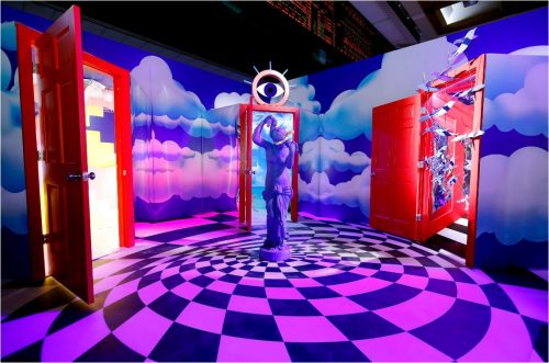 room with clouds painted on walls. 3 red doors, spiral, checkerboard floor. Statue and eye.