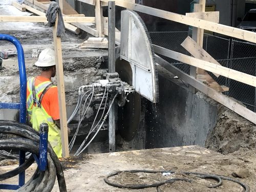 Image of westbound Gardiner Yonge-Bay-York off-ramp work zone, worker saw-cutting retaining wall near the base of the ramp.