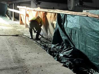 Image of a construction worker chipping the concrete curb along the Gardiner Expressway York-Bay-Yonge off-ramp