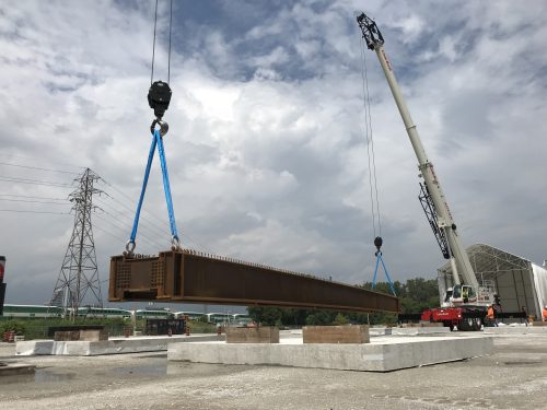 Image of cranes lowering the steel girder onto a concrete platform